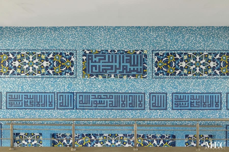 Floral Persian pattern with Kufic Islamic Calligraphy and blue glass mosaic random mixing tiles. Mosque wall cladded Custom handmade ornamental tiles by MEC.