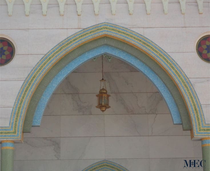 Exterior arches of a mosque cladded with intricately placed glass mosaic tile patterns in a calming aqua and green palette. Custom handcrafted by MEC.