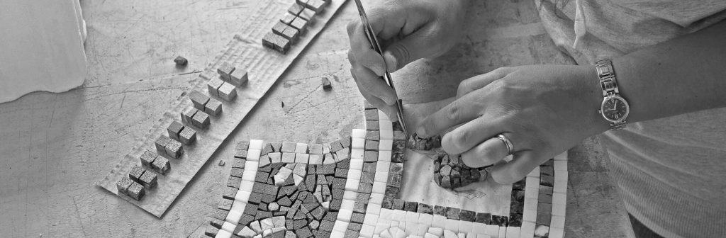 A mosaicist is arranging the marble mosaics in beautiful patterns. 