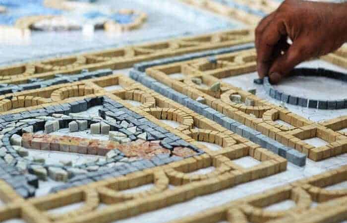 Artistic process, hands crafting a black and white mosaic tile artwork.