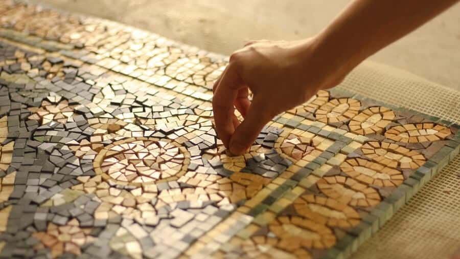 Marble mosaic flooring rug design being handcrafted at a workshop featuring golden hour light