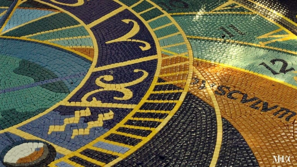 Close-up of a colorful mosaic medallion with intricate patterns and text elements.