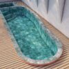 Modern swimming pool with turquoise water and a wooden deck. Outdoor design.
