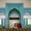 Intricate Moroccan tile niche with geometric patterns in blue and green, inside a building.