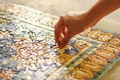 Use mosaic tiles on the floor with marble rugs - mosaic artisans placing a marble tile