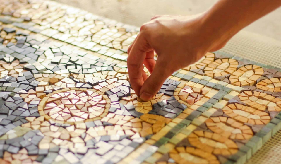 Use mosaic tiles on the floor with marble rugs - mosaic artisans placing a marble tile