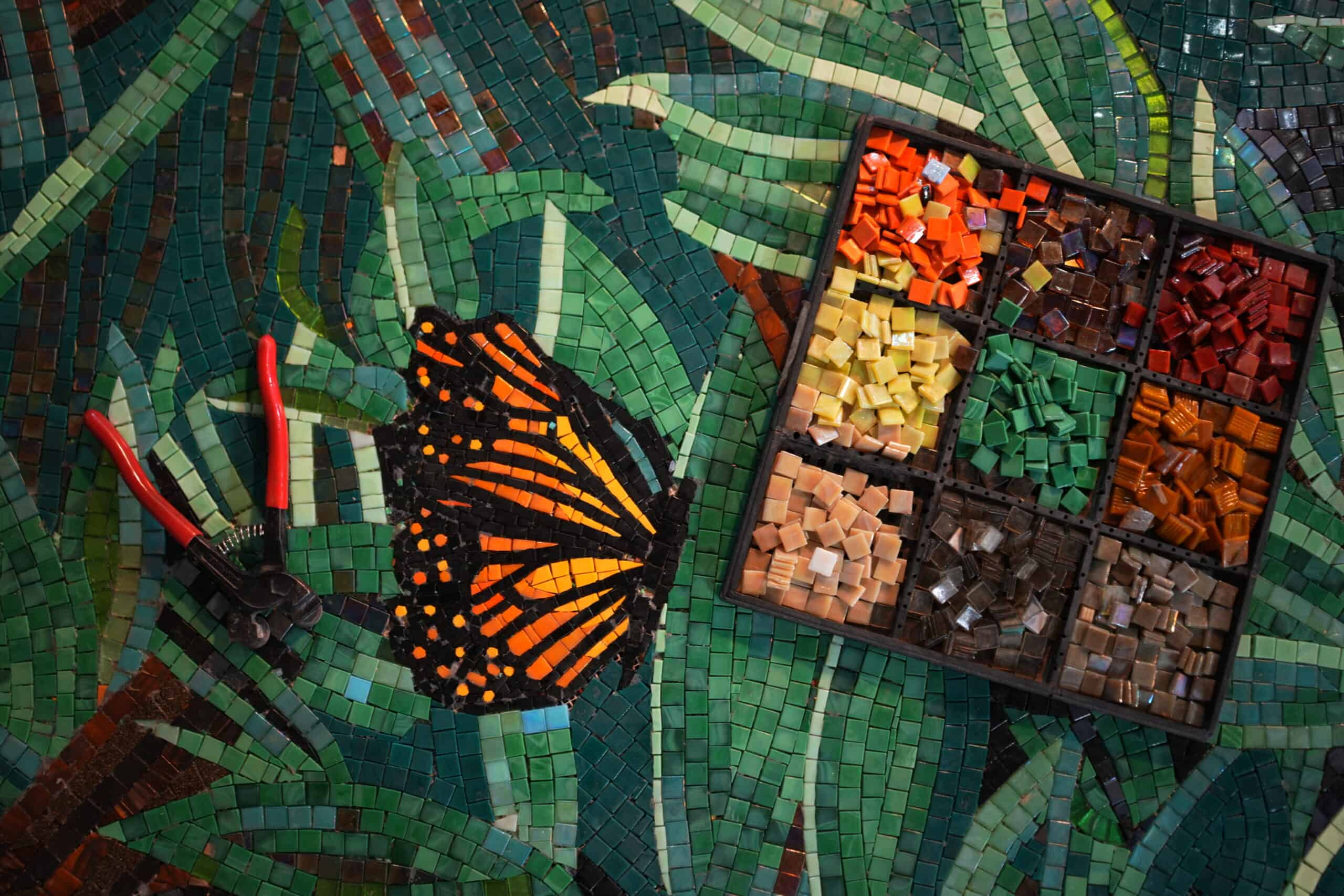glass mosaic mural making behind the scenes. Green leaves, butterfly and glass mosaic tiles