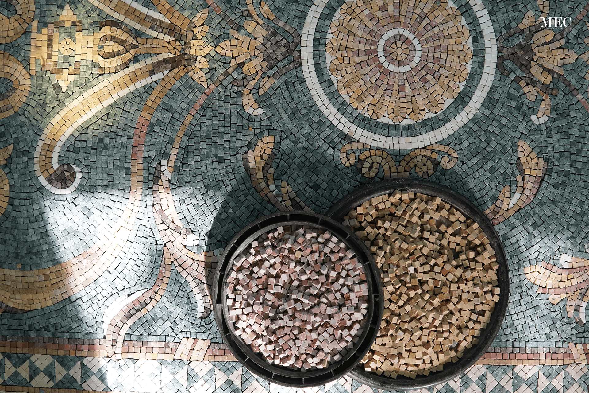 A detailed mosaic floor with two round manhole covers filled with marble mosaics.