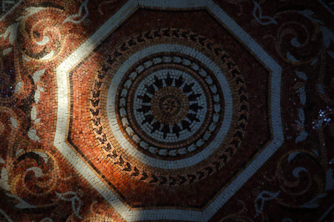 Intricate circular mosaic floor pattern featuring octagonal frame, earthy tones, and ornate floral geometric detailing.