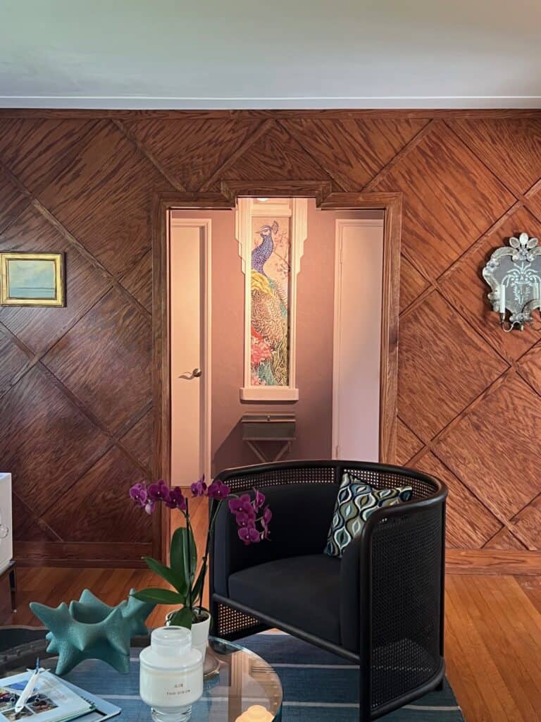 Elegant living space with wood-paneled walls, centered mosaic peacock artwork framed between two doors in hallway.