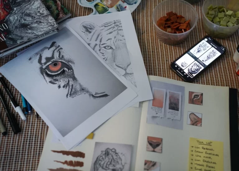 Artistic workspace with tiger sketches, color swatches, mosaic tiles, and reference images on a phone.