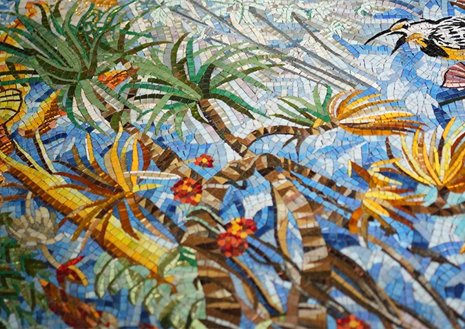 Colorful mosaic of tropical plants and flowers with a bird on a vibrant blue background.