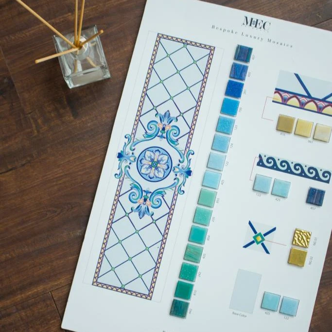 Mosaic sample board featuring blue-toned tiles, design mockups, and color swatches on wooden surface.