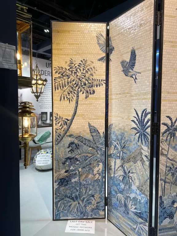 Tropical-themed mosaic folding screen with palm trees and birds, displayed under warm showroom lighting.