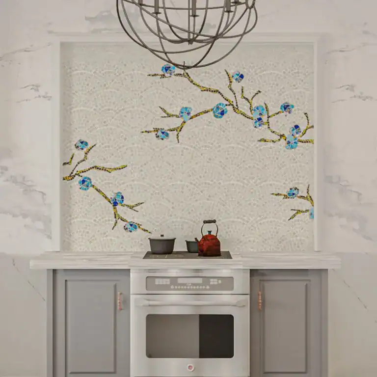Modern kitchen backsplash with delicate mosaic of blue blossoms on gold branches over scalloped white tiles.