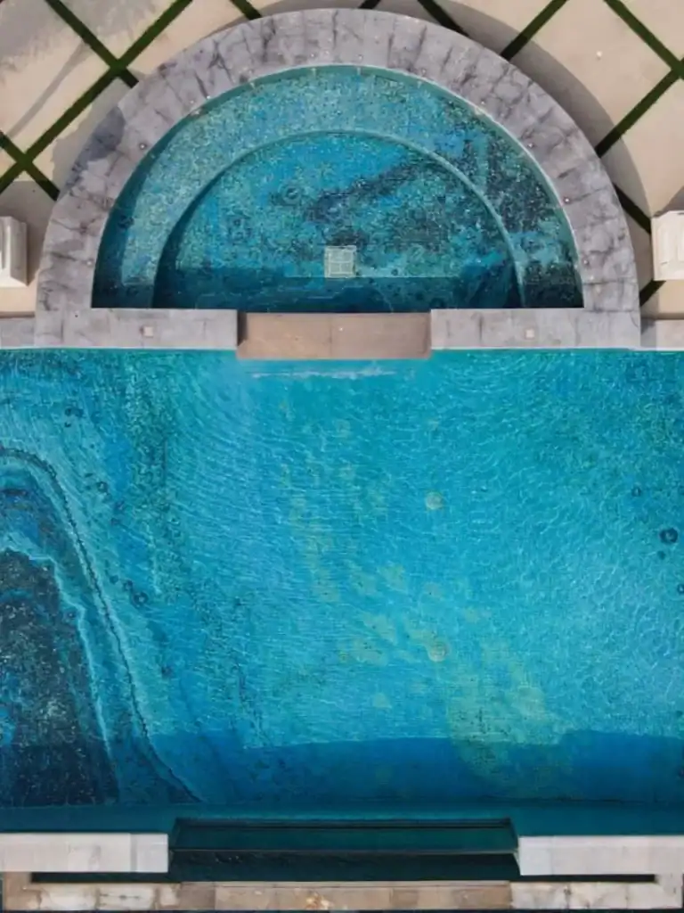 Aerial view of a luxurious mosaic-tiled swimming pool with semicircular spa area above.