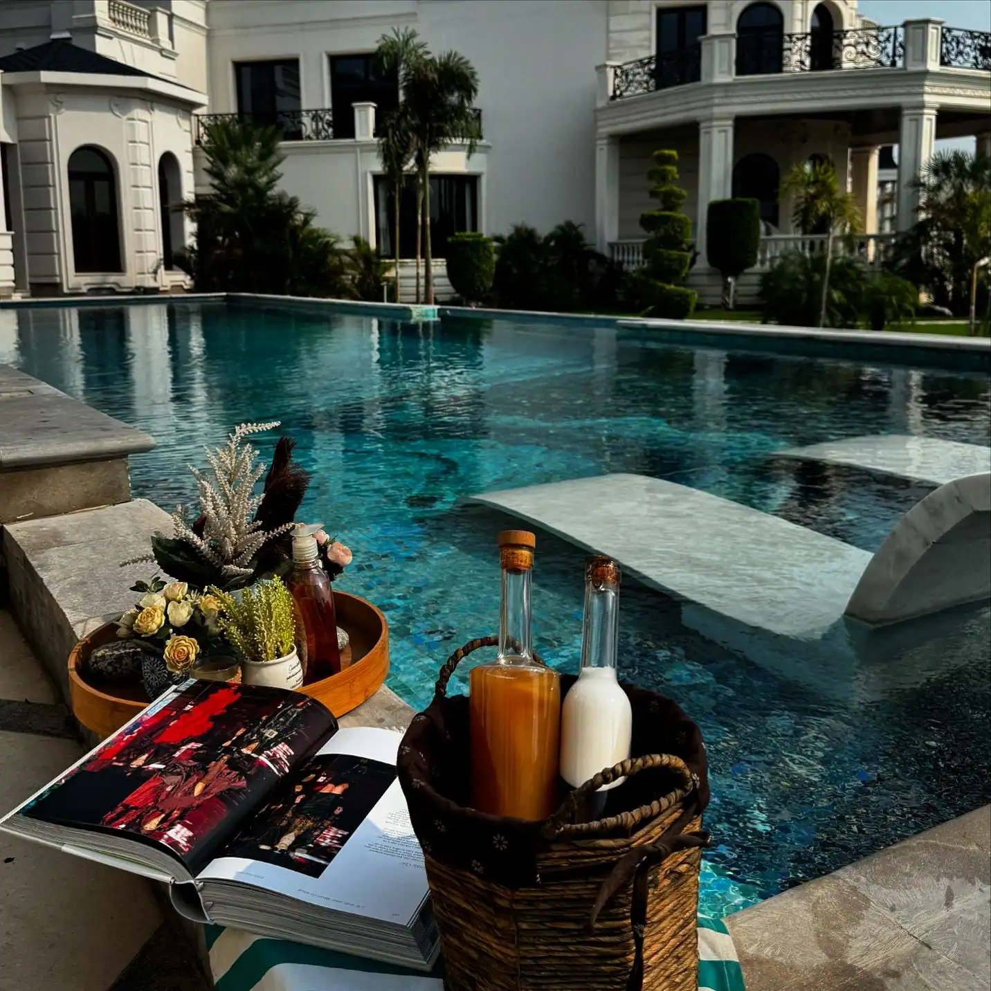 Outdoor villa pool finished with shimmering blue mosaic tiles, featuring in-pool seating and surrounded by elegant architecture.