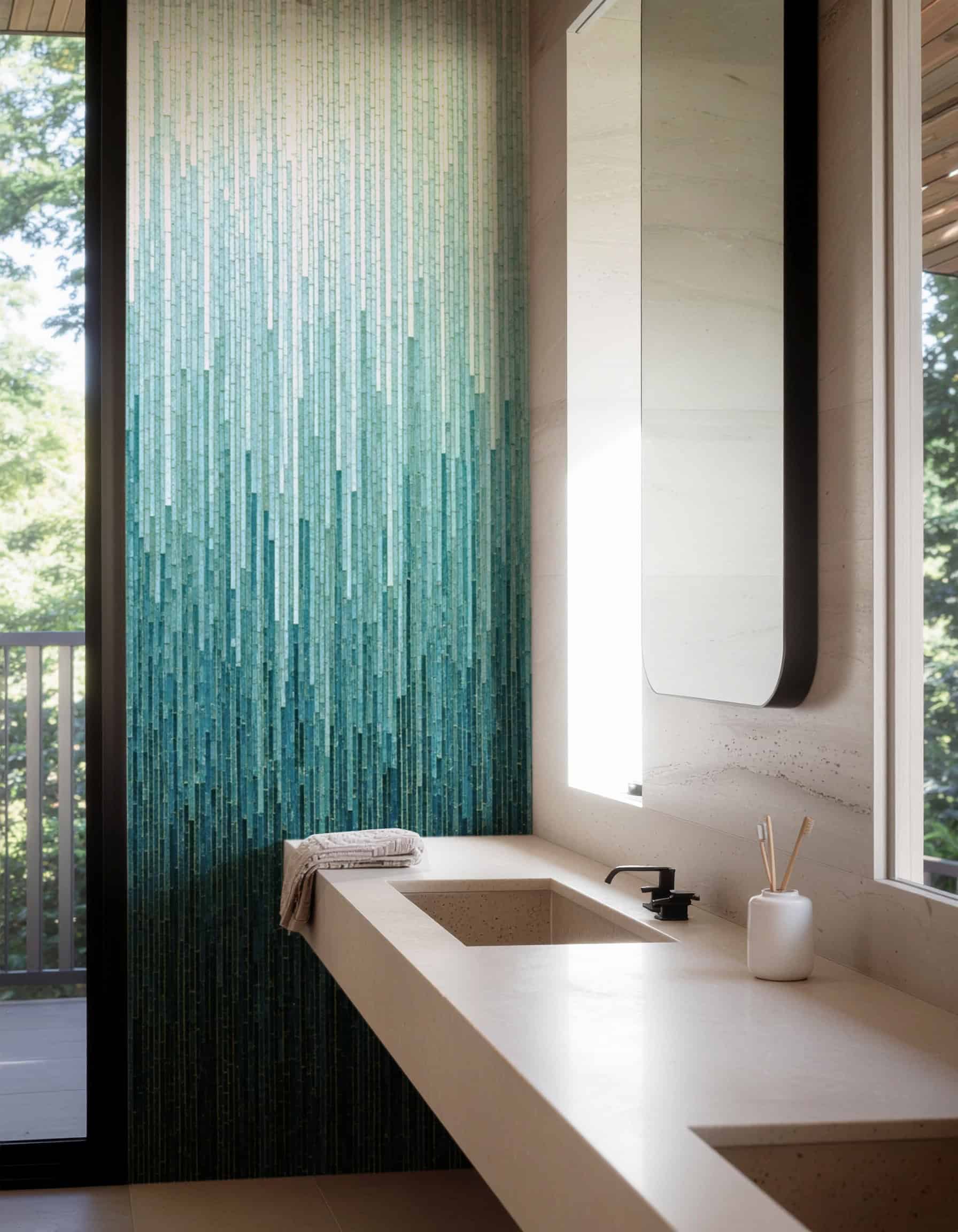 Modern bathroom with a vertical glass mosaic feature wall in gradient blue and teal tones, creating a cascading water effect beside a beige floating vanity.
