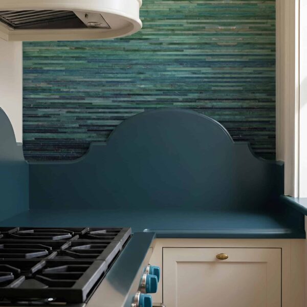 Emerald Tide linear glass mosaic used as a modern kitchen backsplash behind a cooktop, featuring layered green mosaic tones.