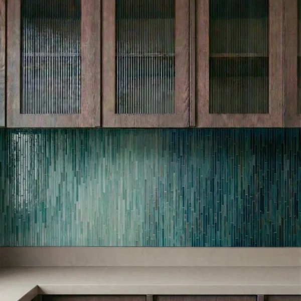 Verdant Depth Ombre Linear Mosaic used as a modern kitchen backsplash with bronze fixtures and dark wood cabinetry.