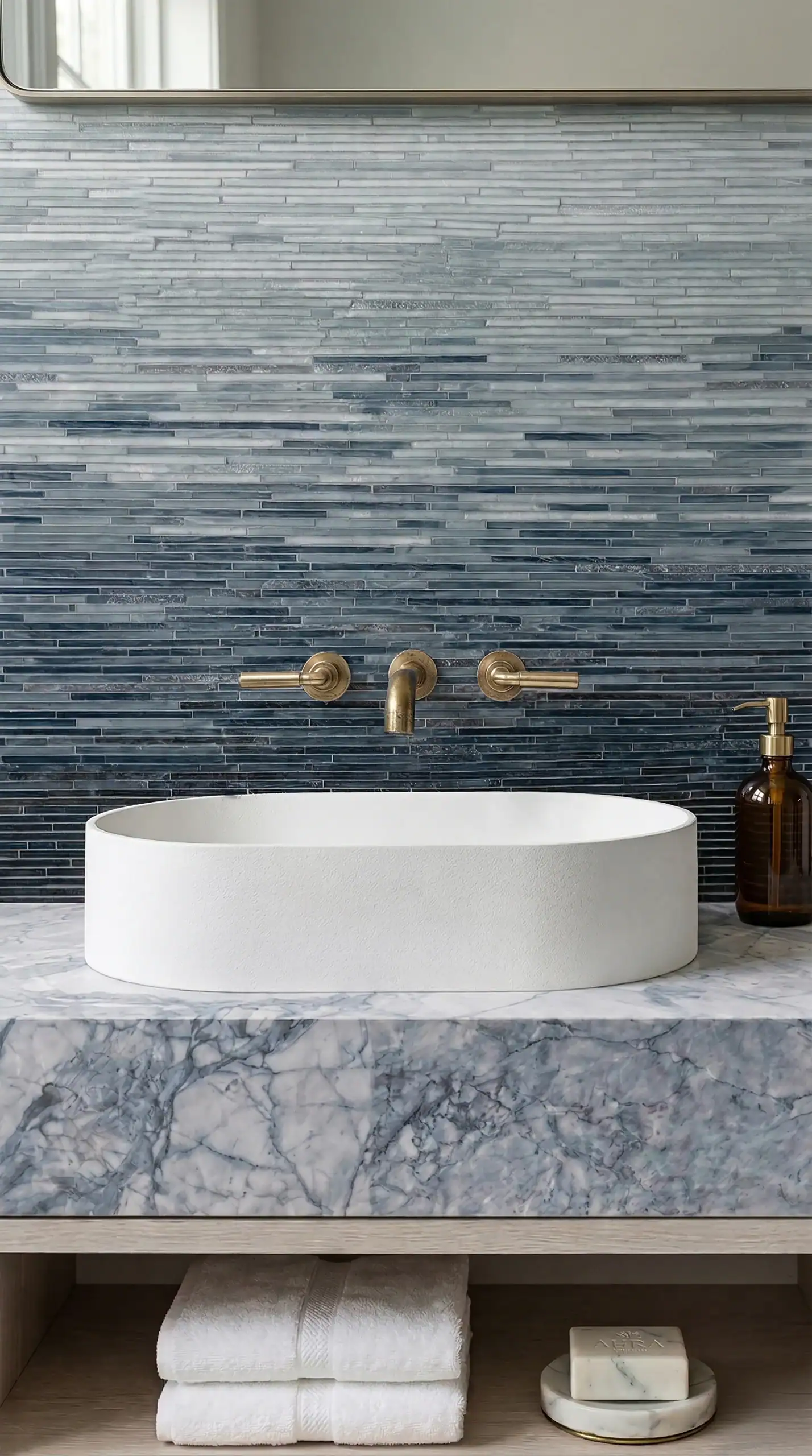 dark blue linear glass mosaic backsplash with gradient tones behind modern white sink in luxury contemporary bathroom interior