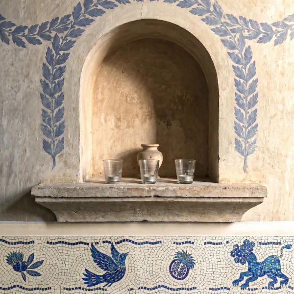 blue and ivory decorative mosaic border with classical motifs and Mediterranean-inspired artistry surrounding a rustic wall niche