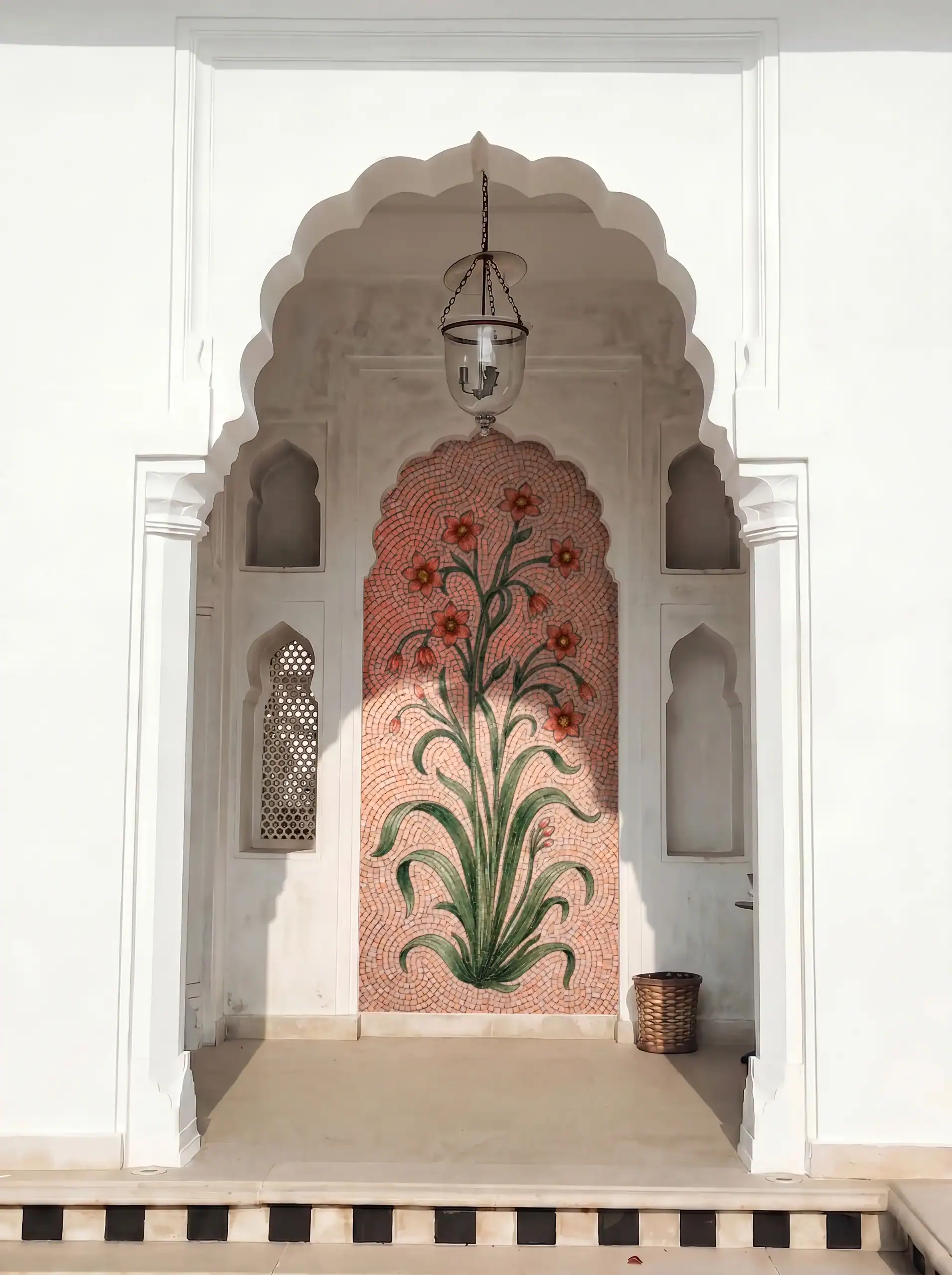 floral mosaic panel in an arched niche featuring blooming flowers and flowing green foliage on a soft coral background