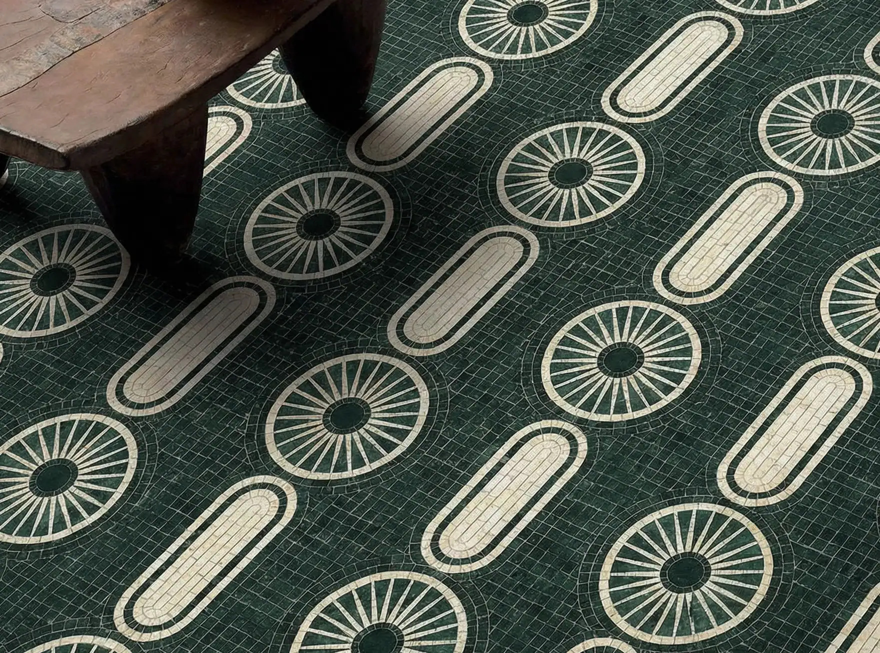 An emerald, marble mosaic floor with a repeating geometric pattern of cream-colored pill shaped design along with wheels under a rustic brown, wooden table.