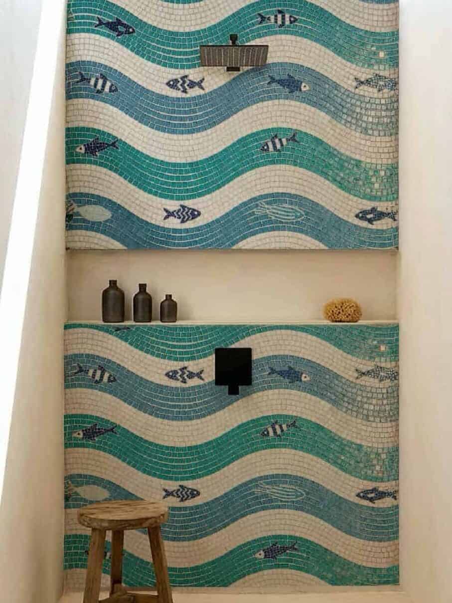 A custom ocean mosaic artwork showcasing a wave pattern in teal and seafoam and white tones, with fishes swimming