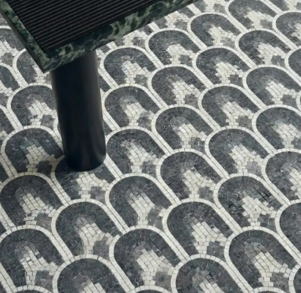 A close-up view of luxury custom flooring featuring a repeating scallop arch layout, offering unique geometric mosaic tile ideas with grey, white, and charcoal stone.
