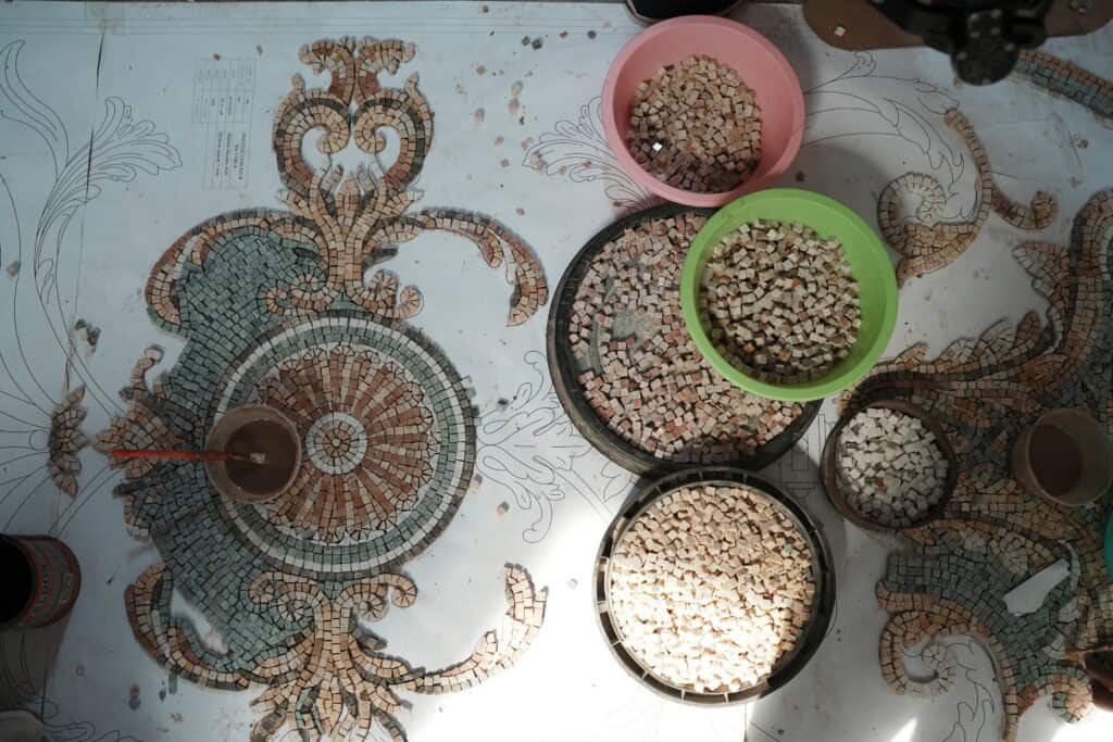 Our artisans at work on a handmade marble mosaic rug.