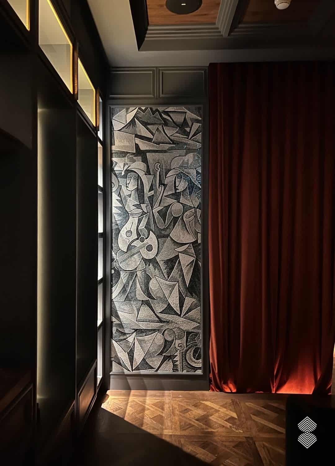 A tall cubist figures wall mosaic showing two musicians in fractured gray and black stone tesserae, installed on a cafe wall.