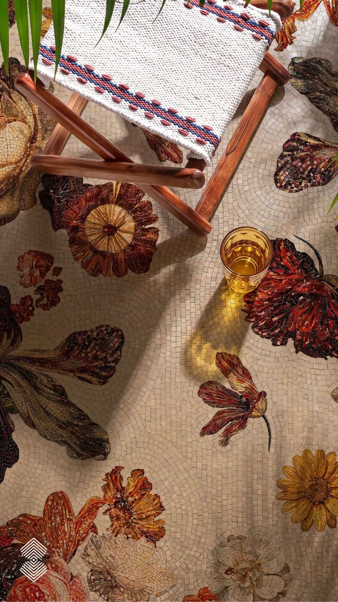 A floral mosaic walkway made of hand-cut stone tesserae showing layered amber and burgundy flowers set into a cream stone garden path.