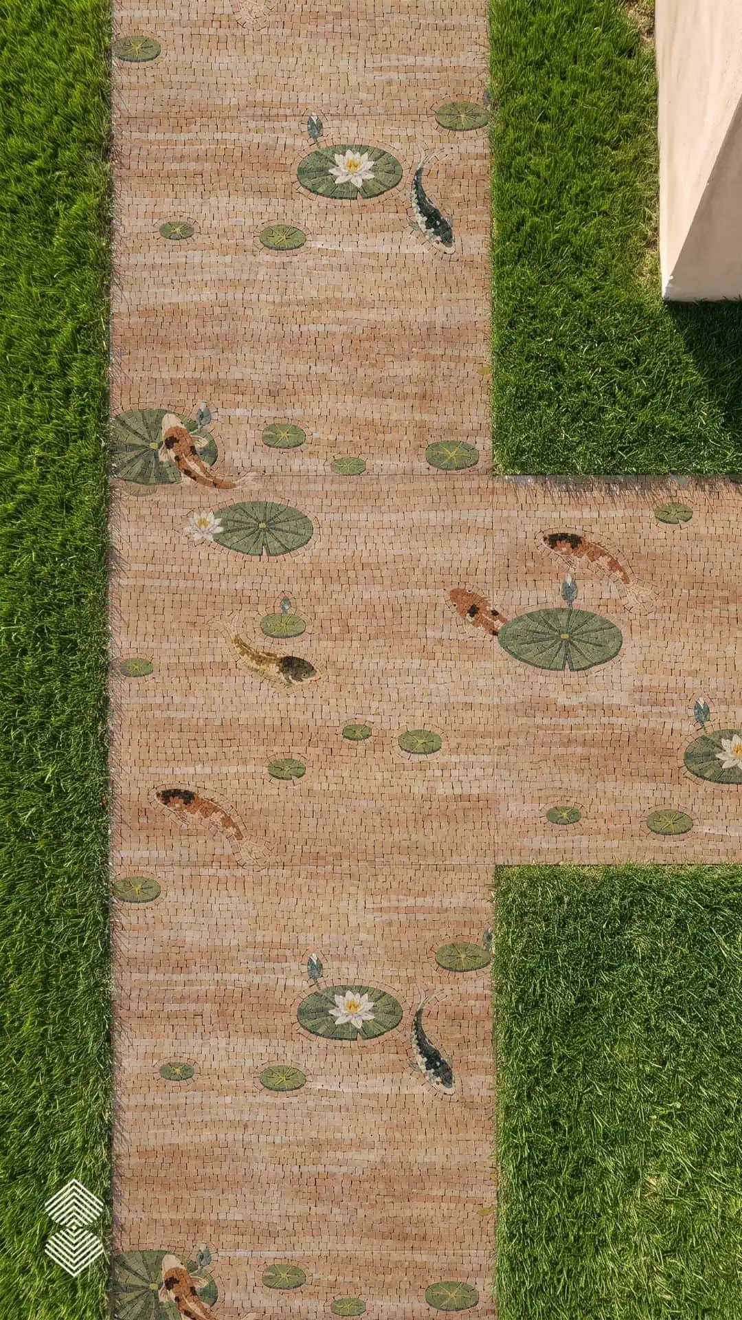 Overhead view of a koi pond walkway mosaic showing orange and black koi swimming among green lily pads set in a stone path