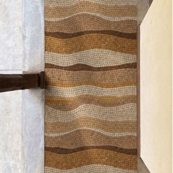 Amber Wave Walkway Mosaic A long wave mosaic walkway panel of amber, gold and cream tesserae installed in a narrow entry corridor between two columns.