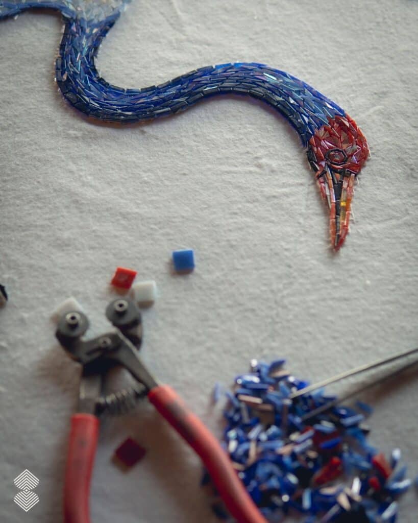 Close-up of hand-cut glass mosaic tiles forming intricate bird neck and face details