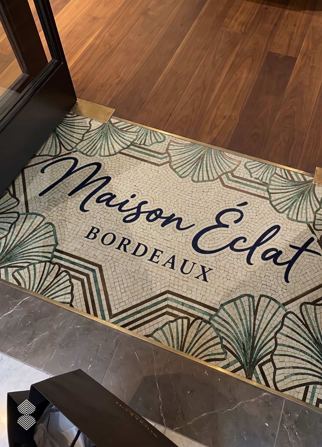 Art Deco Ginkgo Lettered Mosaic with ginkgo leaf border set into a shop entrance floor between wood and marble