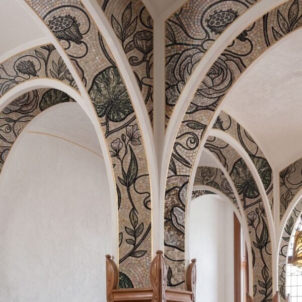 An art nouveau arch mosaic of stylized flowers and leaves covering a groin vault and its arches.