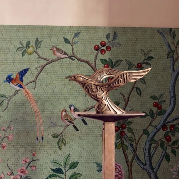 A bird blossom mosaic mural on a sage-green wall showing birds perched on flowering branches with red berries