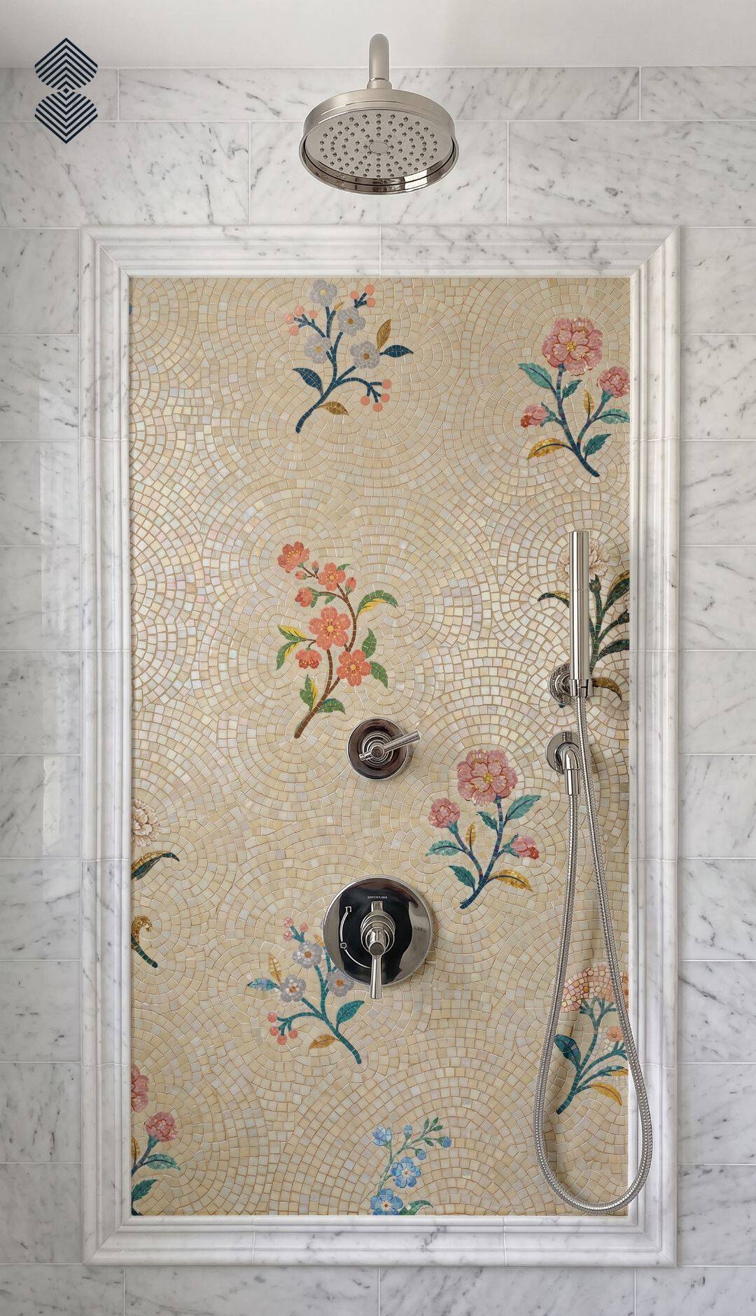 A floral sprig mosaic tile panel with pink and blue blossoms installed as a framed shower wall accent.