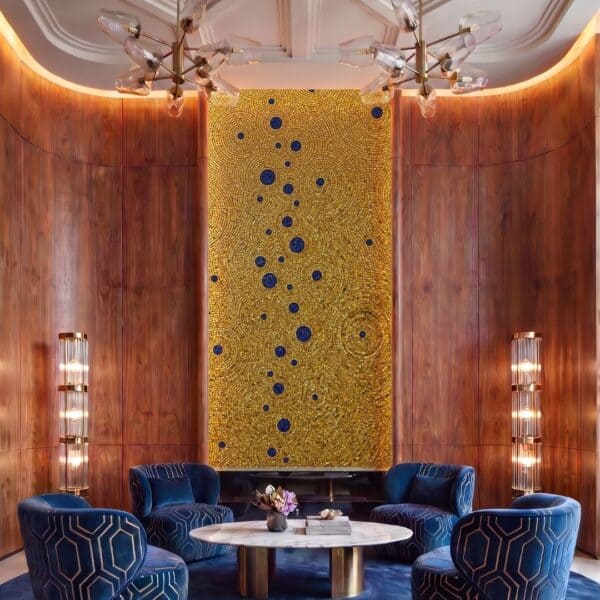 A tall gold circle mosaic panel with concentric gold rings and scattered cobalt blue dots on a feature wall.