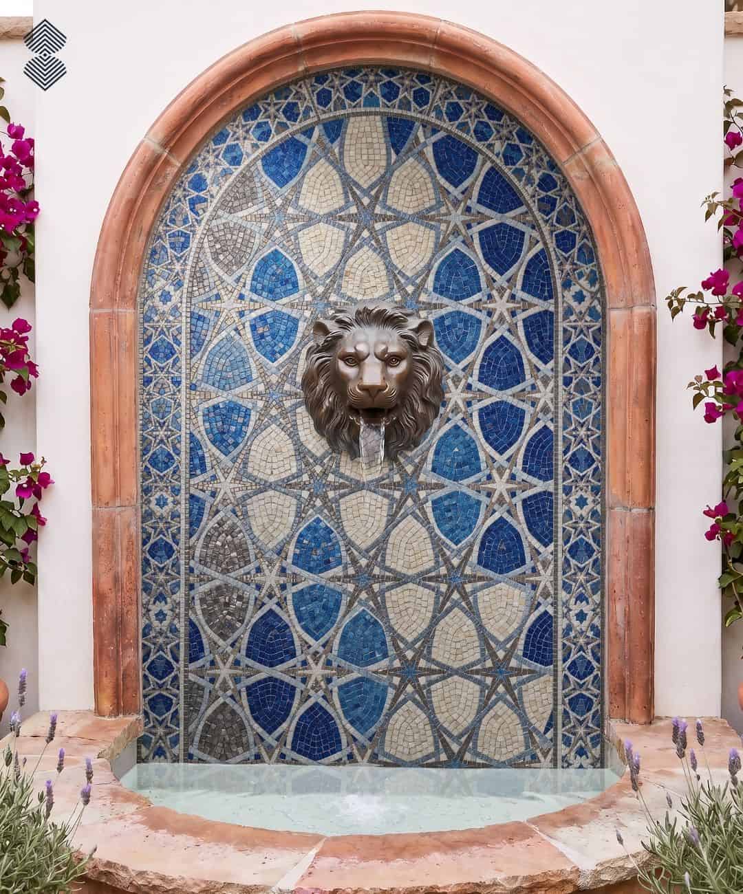 An arched lion head mosaic fountain with a blue and cream eight-point star pattern and a bronze lion head spout.