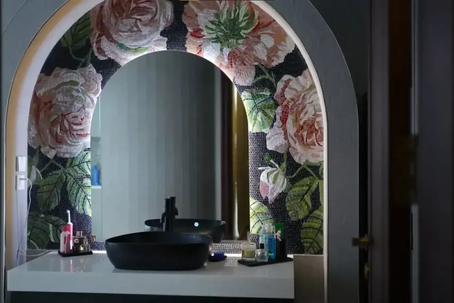 Vanity arch with floral mosaic backdrop, black basin, and soft lighting creating a luxurious ambiance.