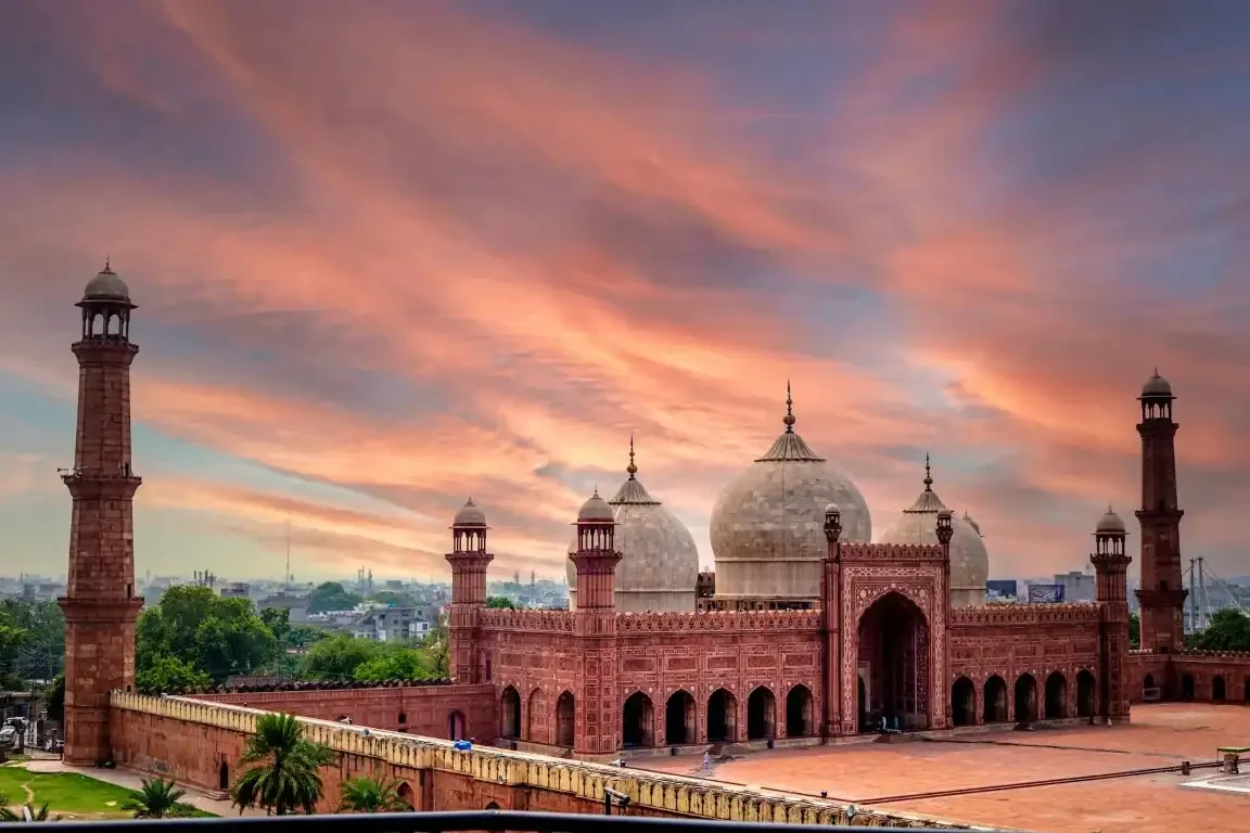 Badshahi Mosque in Lahore at sunset, with dramatic sky and red sandstone architecture glowing beautifully.