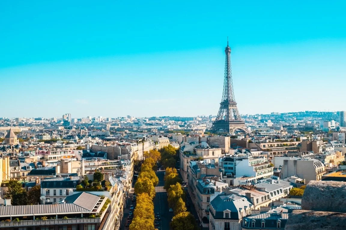 Eiffel Tower rises over Paris skyline on a clear day with classic French architecture below.