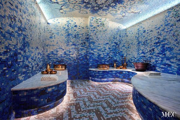 Luxurious spa room with immersive blue mosaic tile walls and ceiling featuring abstract floral designs.