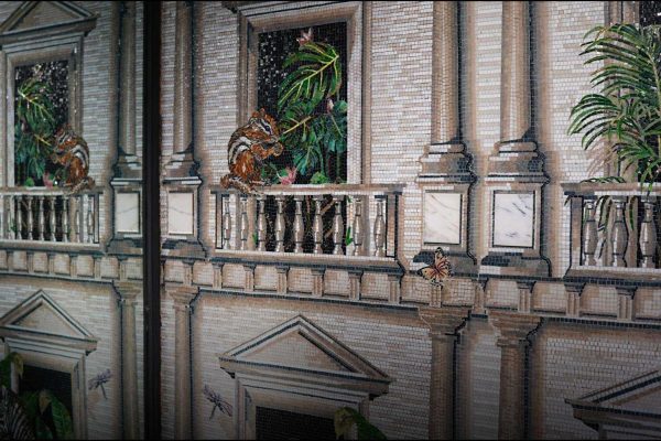 Architectural mosaic mural depicting classical balconies with lush plants, monkeys, butterflies, and tropical wildlife details.