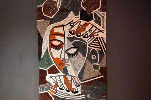Cubist face mosaic art panel showing a fractured stone and glass portrait mounted on a dark restaurant wall